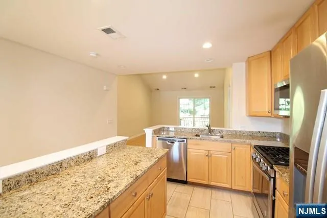 a view of a kitchen with a sink wooden cabinets and stainless steel appliances