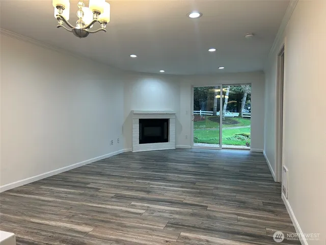 a view of kitchen and empty room with wooden floor