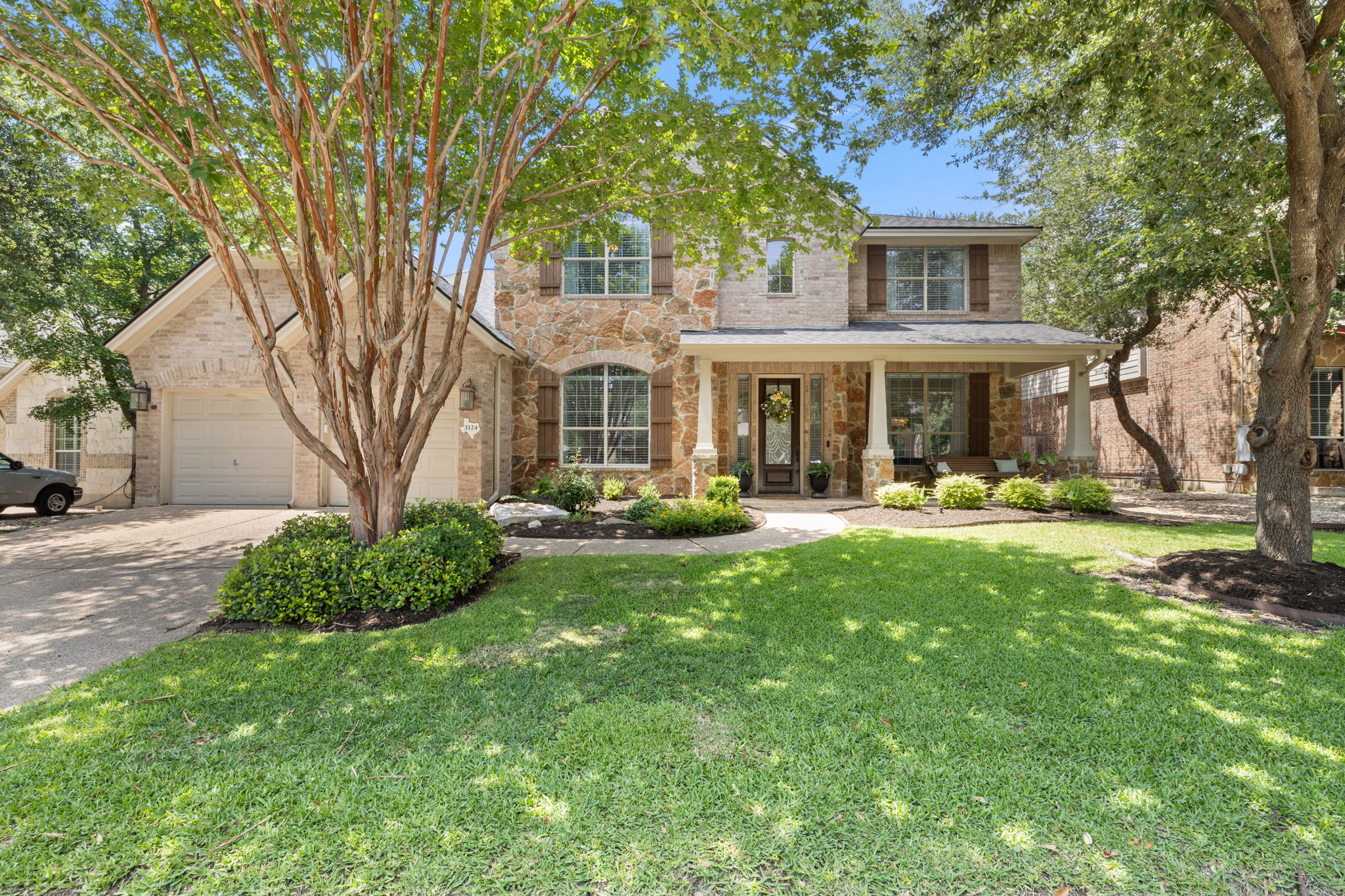 1124 Castle Path Round Rock, TX 78681 - Photo 1 of 40 A welcoming stone and brick facade with a covered porch and mature trees define this home's character.
