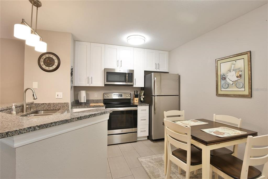 850 South Tamiami Trail, Unit 409 Sarasota, FL 34236 - Photo 6 of 22 a kitchen with stainless steel appliances granite countertop a sink a stove a refrigerator with a dining table and chairs