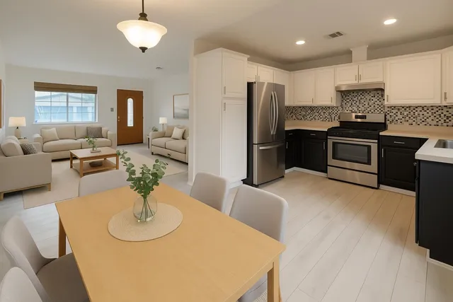 a kitchen with stainless steel appliances granite countertop a refrigerator a stove a sink a dining table and chairs