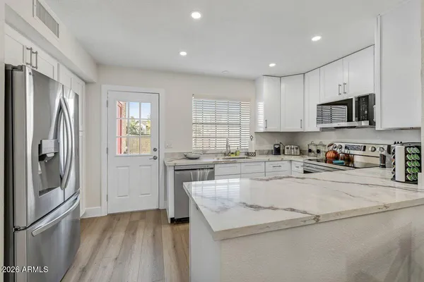 a kitchen with stainless steel appliances granite countertop a refrigerator a stove a sink and a microwave
