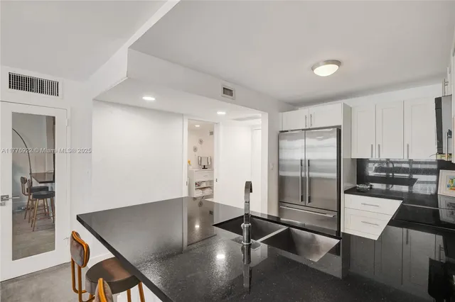a kitchen with stainless steel appliances granite countertop a sink refrigerator and cabinets