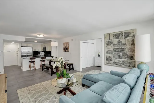 a living room with furniture kitchen view and a window