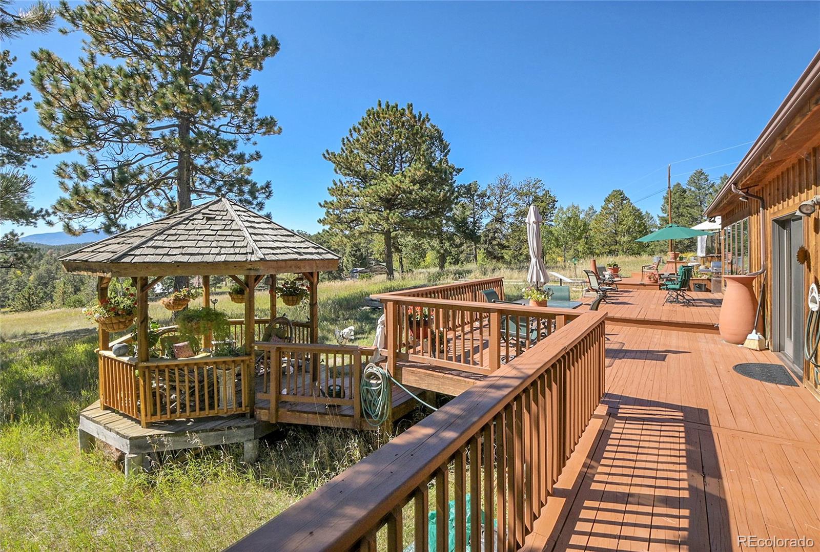 13082 South Wamblee Valley Road Conifer, CO 80433 - Photo 25 of 35 a view of a brick house with large trees and wooden fence