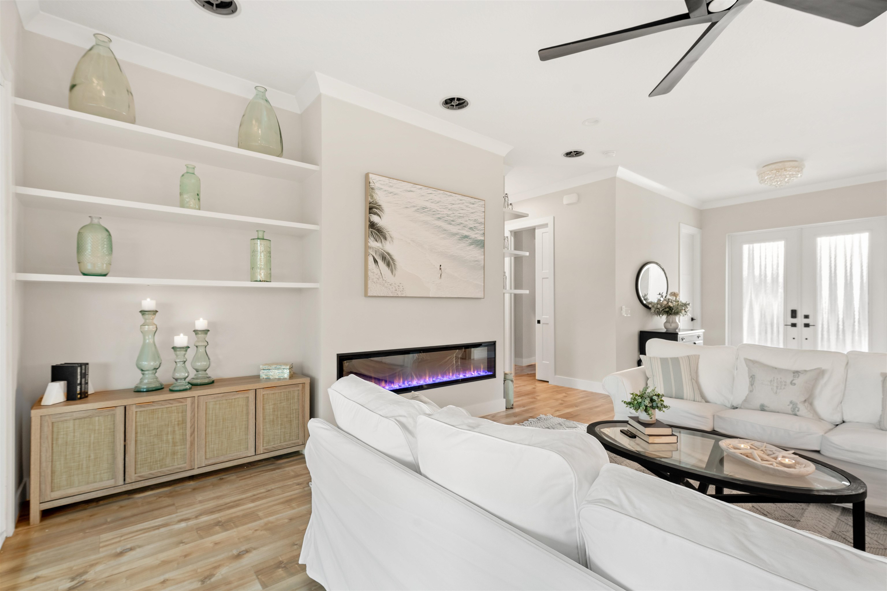 2549 Palm Avenue Flagler Beach, FL 32136 - Photo 33 of 70 Living room featuring built in shelves, light wood-style flooring, a glass covered fireplace, ceiling fan, and ornamental molding