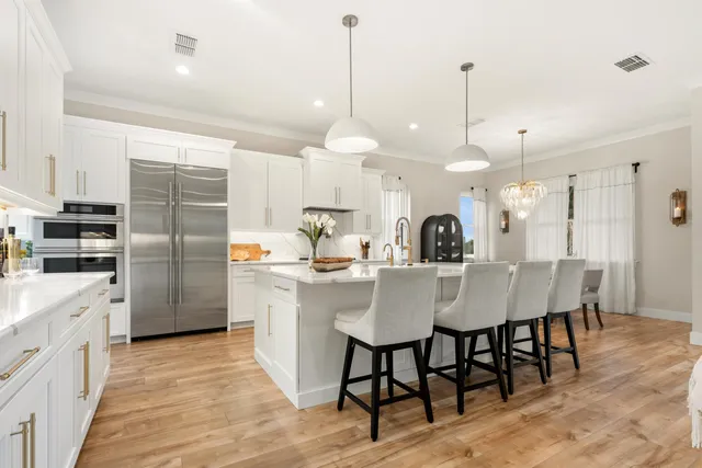 a kitchen with stainless steel appliances a dining table chairs and white cabinets