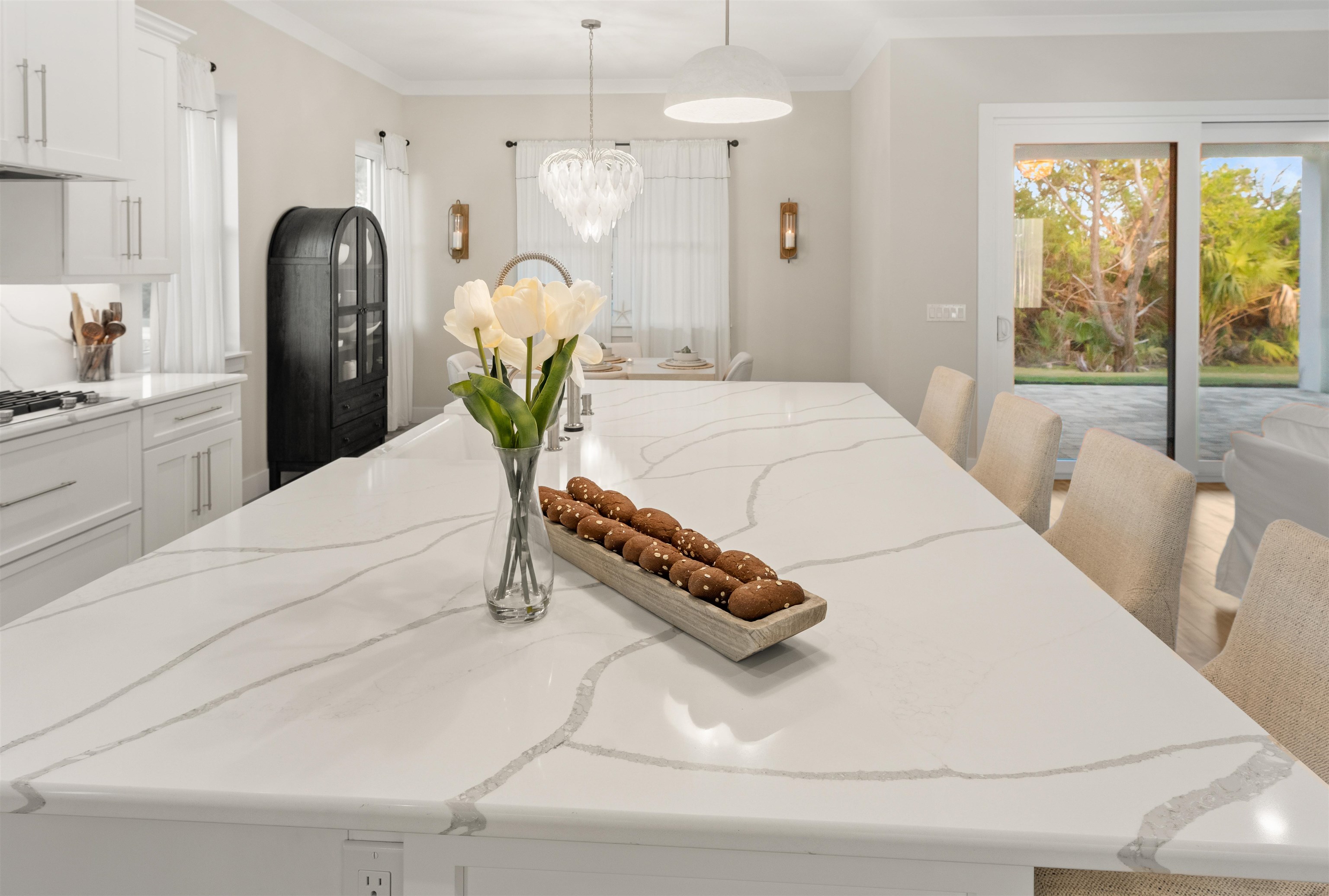 2549 Palm Avenue Flagler Beach, FL 32136 - Photo 6 of 65 Kitchen with white cabinets, ornamental molding, hanging light fixtures, light stone counters, and a kitchen breakfast bar