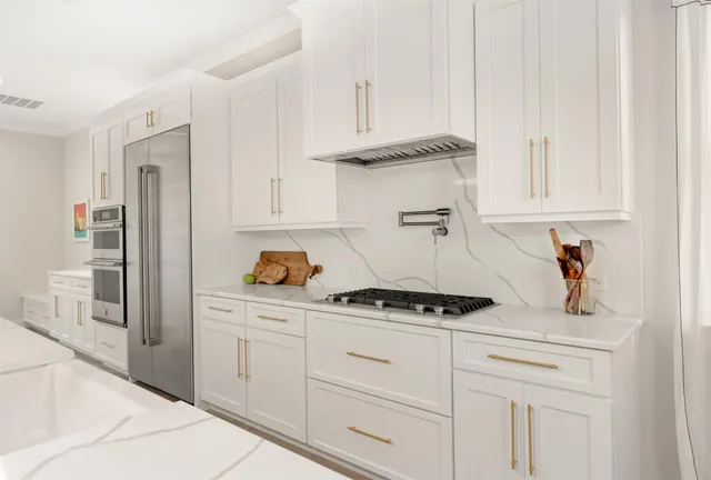 a kitchen with stainless steel appliances granite countertop a stove and white cabinets