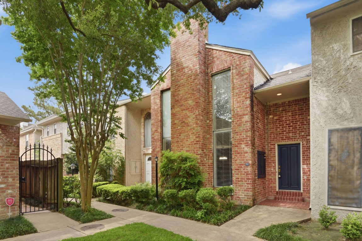 Stunning brick townhome exterior with trees and manicured landscaping