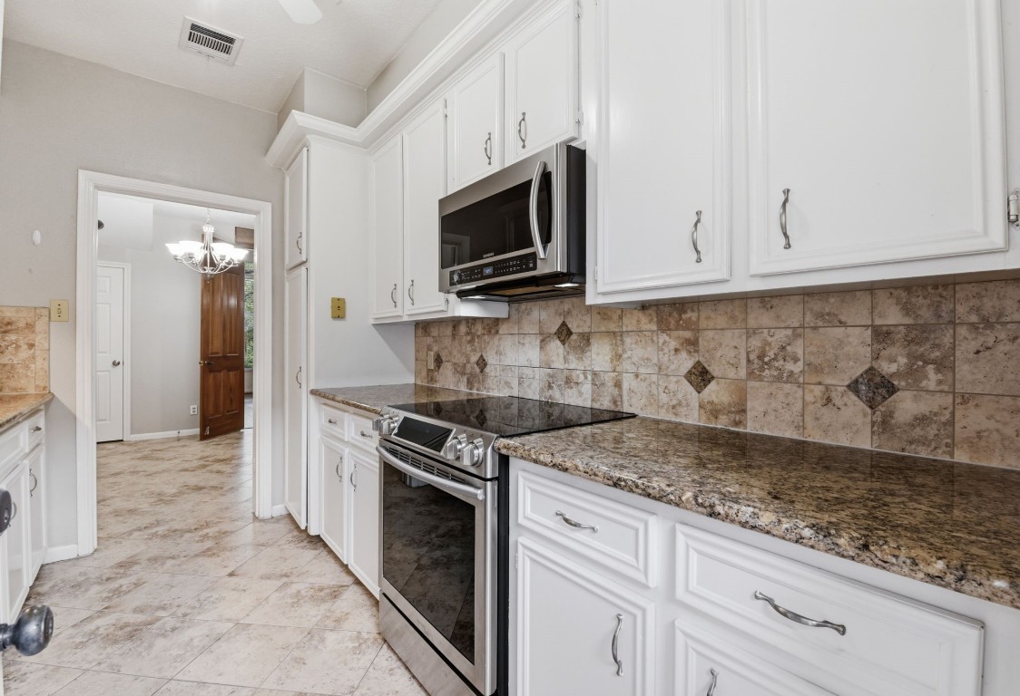 727 Bunker Hill Road, Unit 34 Houston, TX 77024 - Photo 19 of 50 Gorgeous kitchen featuring white cabinetry, stainless steel appliances, stone backsplash, and granite countertops