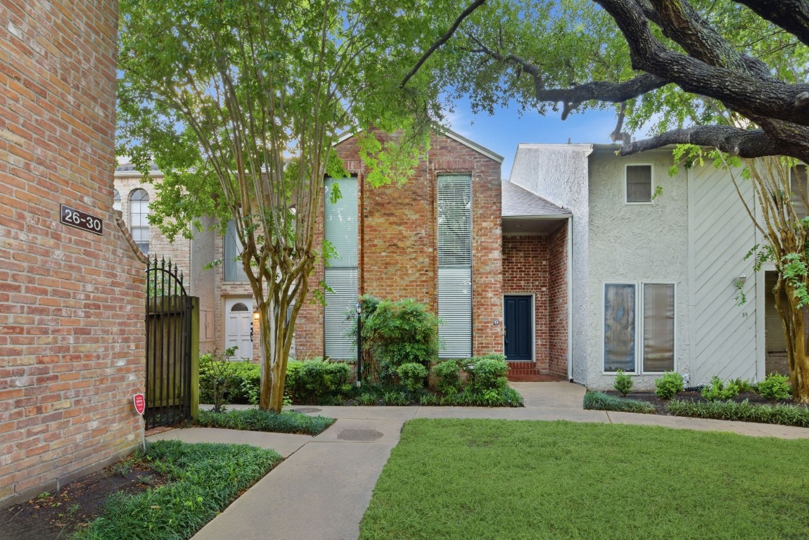 727 Bunker Hill Road, Unit 34 Houston, TX 77024 - Photo 3 of 50 Charming brick townhome nestled among mature trees with lush landscaping, manicured lawn, and a welcoming walkway