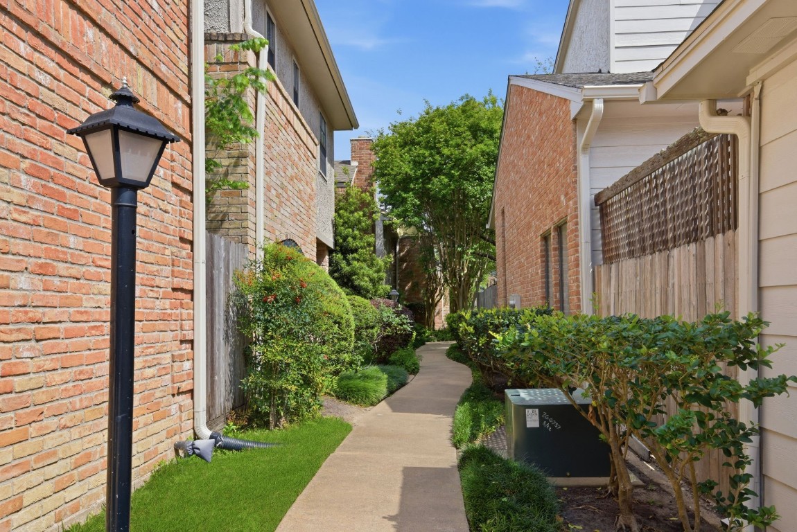 727 Bunker Hill Road, Unit 34 Houston, TX 77024 - Photo 46 of 50 Welcoming walkway with lush landscaping, brick exteriors, and classic lamp post