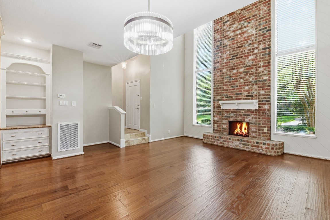 727 Bunker Hill Road, Unit 34 Houston, TX 77024 - Photo 5 of 50 Living room boasting floor-to-ceiling stone fireplace, gleaming hardwood floors, and elegant built-in shelving