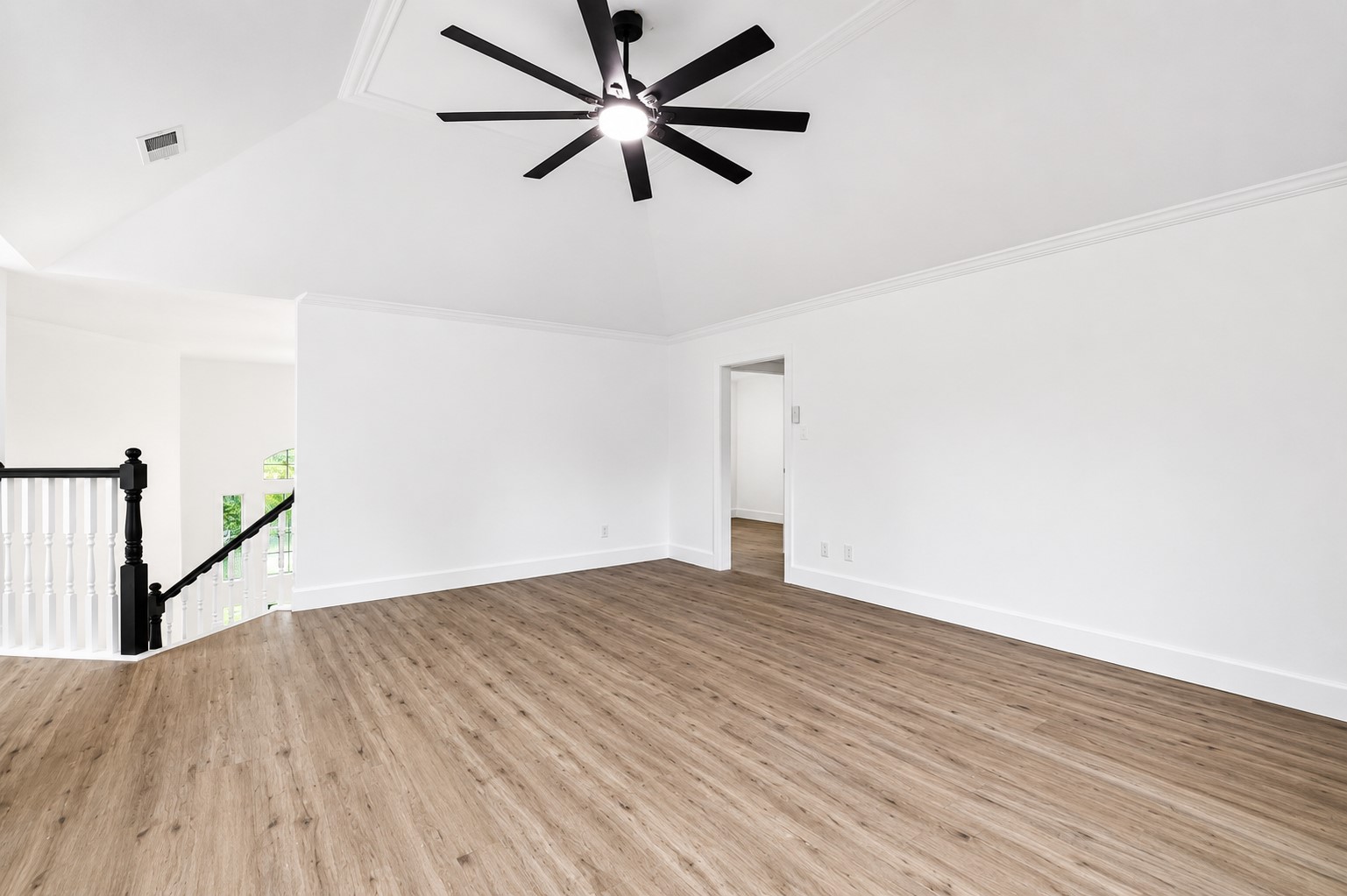 523 Rampart Lane Conroe, TX 77302 - Photo 21 of 41 Spacious upstairs loft with soaring vaulted ceilings, luxury vinyl plank flooring, and a modern oversized ceiling fan. This versatile flex space is ideal for a game room, media room, home office, fitness area, or secondary living room, offering endless possibilities to fit your lifestyle.
