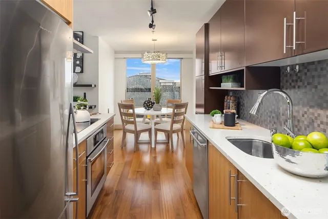 a kitchen with stainless steel appliances granite countertop a stove top oven a dining table and chairs with wooden floor