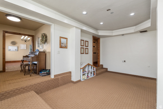 892 Cambridge Drive St. George, UT 84770 - Photo 12 of 65 Recessed lighting illuminates a carpeted open area with a tray ceiling design and a built-in shelf unit