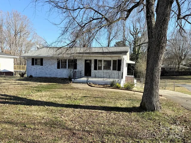 a front view of a house with a yard tree and wooden fence