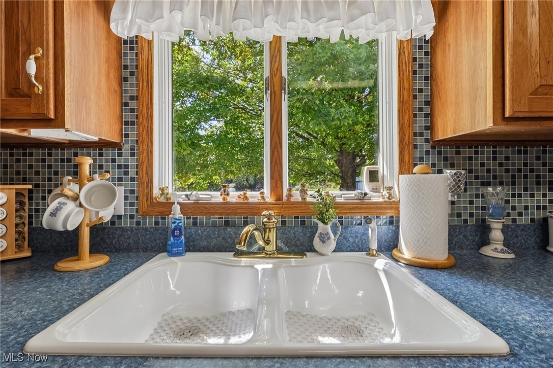 6130 Warren - Sharon Road Brookfield, OH 44403 - Photo 17 of 50 Kitchen view of tasteful backsplash, blue countertops, and quality wood cabinets, white sink with peaceful view to backyard