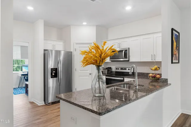 a kitchen with stainless steel appliances granite countertop a refrigerator a stove and a sink