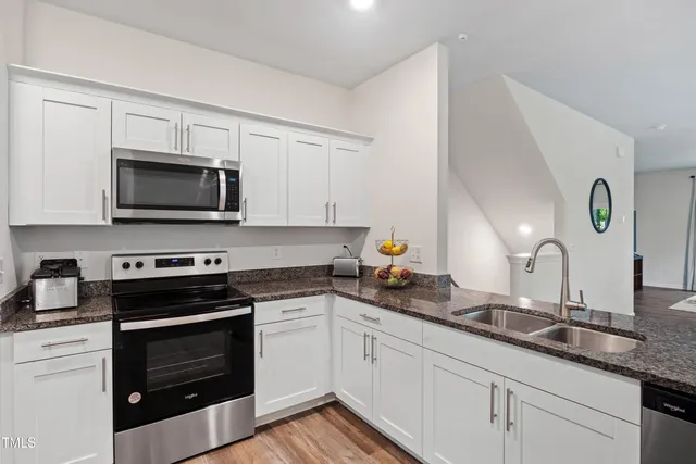 a kitchen with granite countertop a stove a sink and a microwave