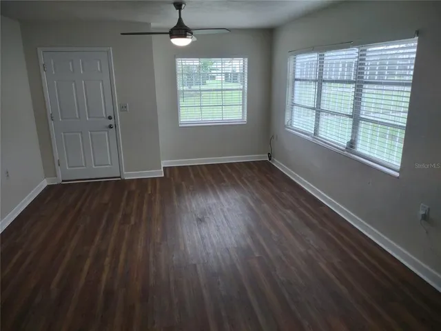 an empty room with wooden floor and windows