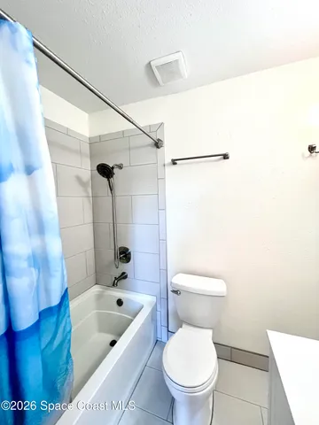 a white toilet sitting next to a bath tub and a shower