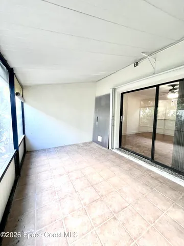 a view of an empty room with wooden floor and windows