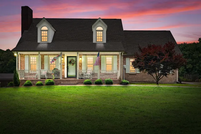 a view of a brick house with a big yard and large trees