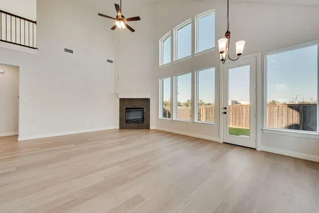 an empty room with wooden floor fireplace and windows