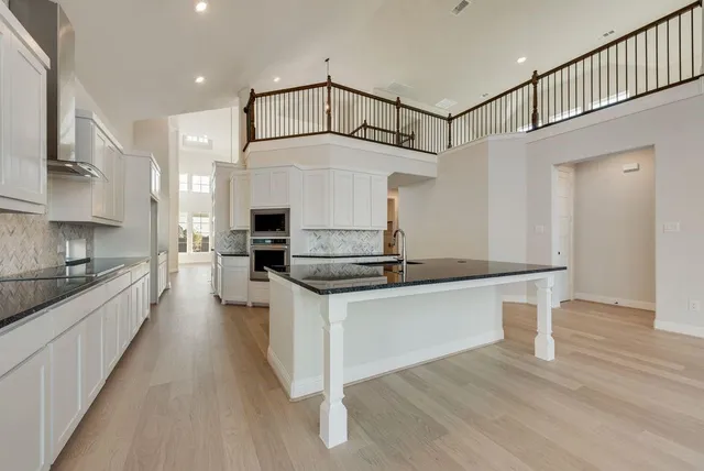 a kitchen with stainless steel appliances granite countertop a sink a stove and a wooden floors