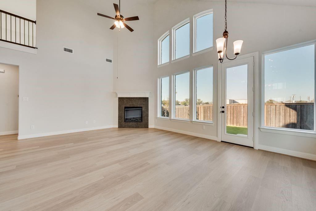 1329 Sundance Lane Justin, TX 76247 - Photo 10 of 37 an empty room with wooden floor fireplace and windows