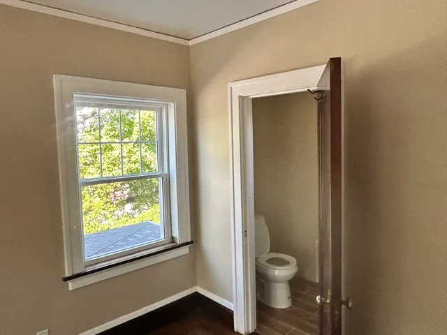 a bathroom with a granite countertop toilet a sink a window and a shower