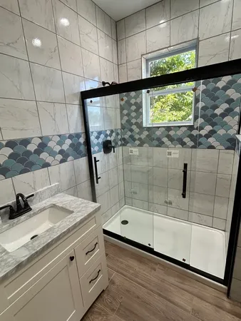 a bathroom with a granite countertop sink a mirror and shower
