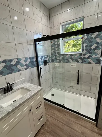 a bathroom with a granite countertop sink a mirror and shower