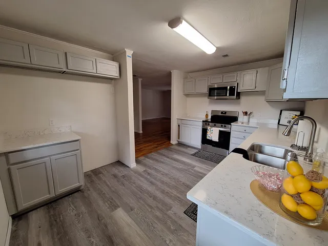 a kitchen with stainless steel appliances a sink a stove a refrigerator cabinets and wooden floor