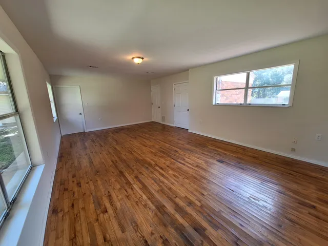 a view of an empty room with wooden floor and a window