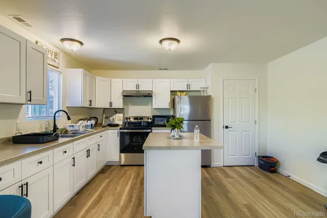 a kitchen with a sink a refrigerator and white cabinets