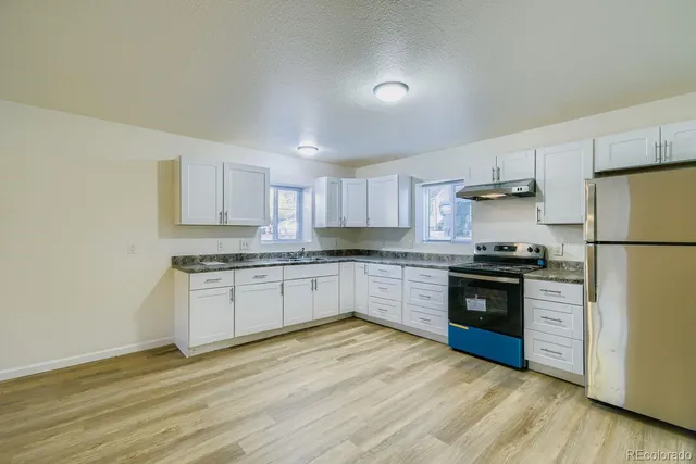 a kitchen with granite countertop a refrigerator stove top oven and sink