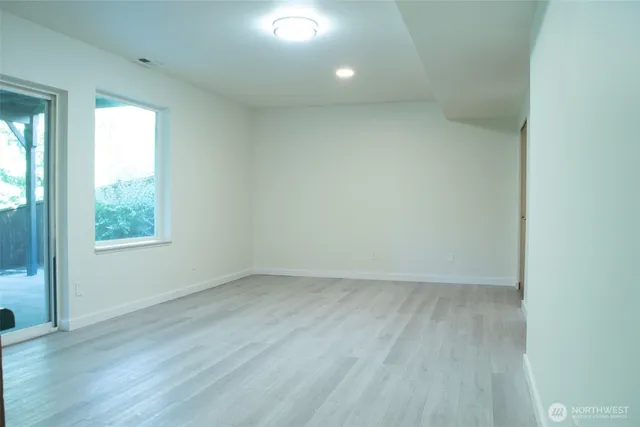 an empty room with wooden floor and windows