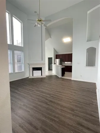 an empty room with wooden floor fireplace and windows