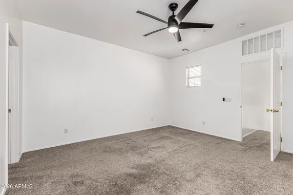 an empty room with ceiling fan and window