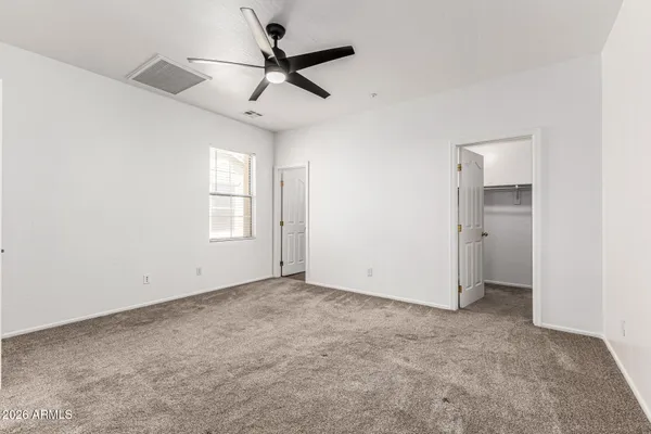 an empty room with a ceiling fan and windows