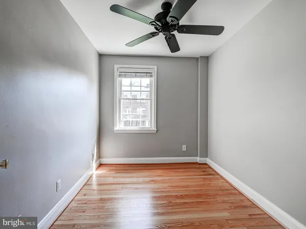 an empty room with wooden floor fan and windows
