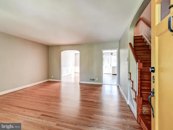 a view of an empty room with wooden floor and stairs
