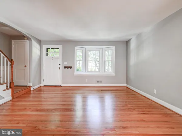 a view of an empty room with window and wooden floor
