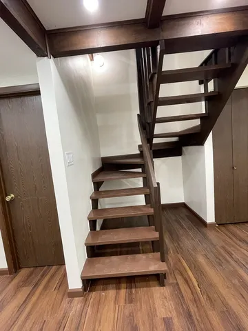 a view of an empty room with wooden floor and stairs
