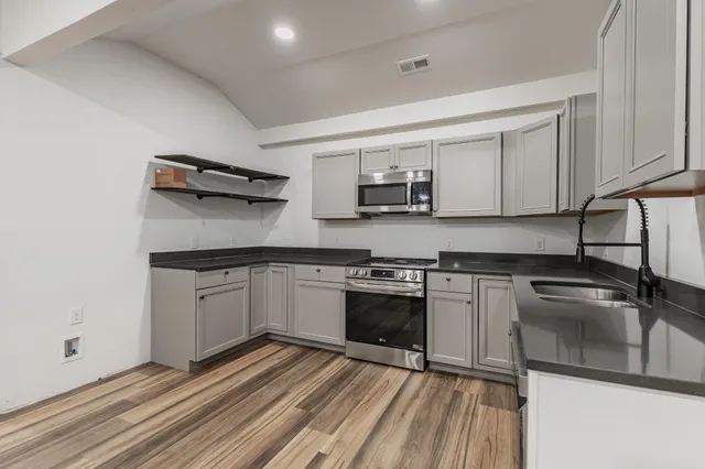 a large white kitchen with wooden floor and a sink