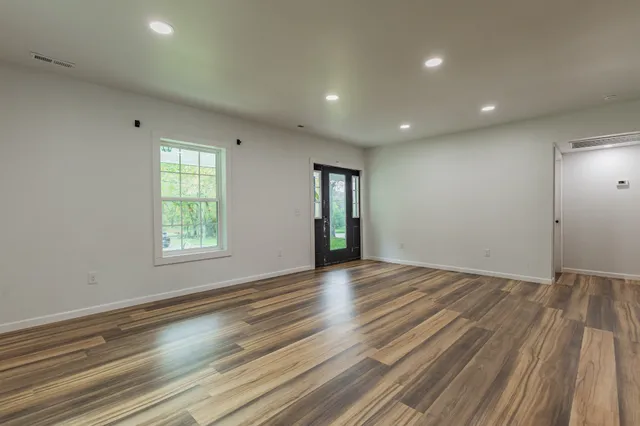an empty room with wooden floor and windows
