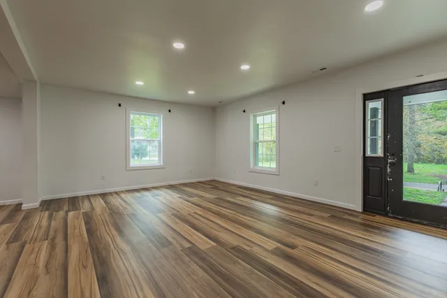 a view of an empty room with wooden floor and a window